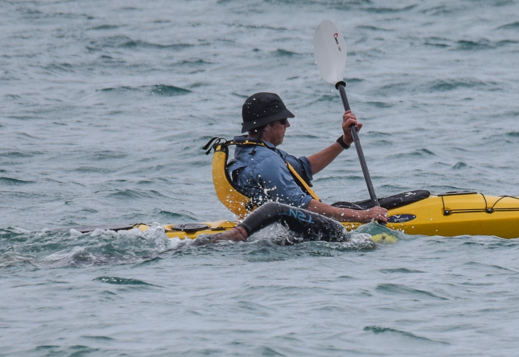 Kayak paddler beside ocean swimmer